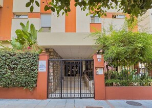 Une entrée fermée par un portail mène à un immeuble sur lequel une plaque indique qu’il s’agit du sixième bâtiment du complexe Apolo.