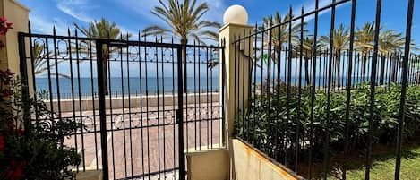 A gated entrance to a property with a view of the beach and palm trees.