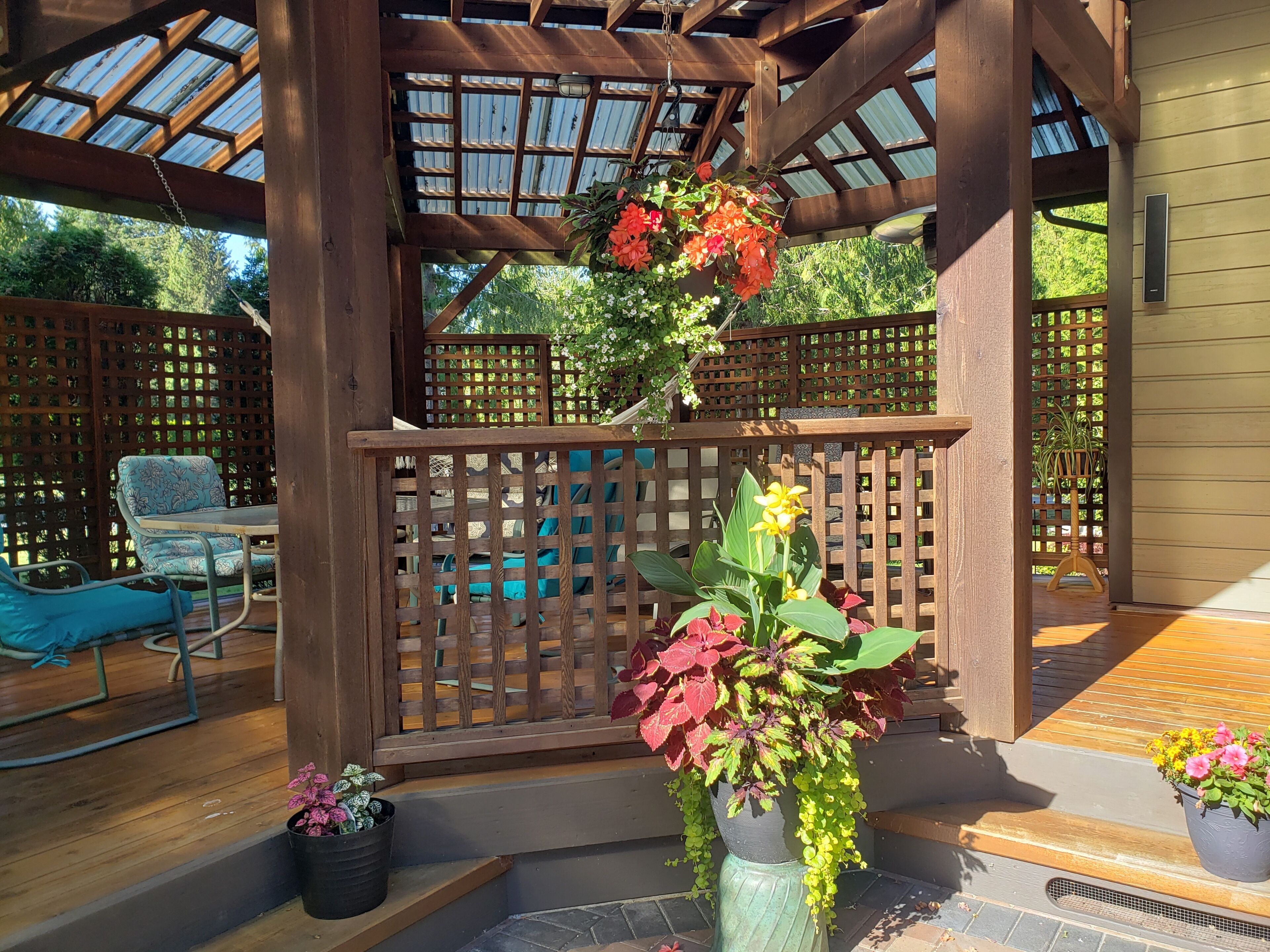 Une terrasse en bois agrémentée d’une pergola, de meubles d’extérieur et de plantes en pot.
