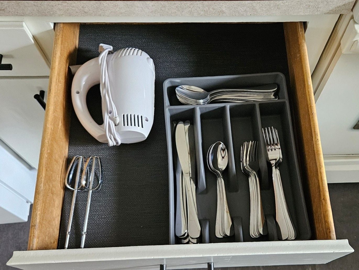 Un tiroir contenant une tasse blanche, des couverts et une cuillère.