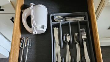 Un tiroir contenant une tasse blanche, des couverts et une cuillère.