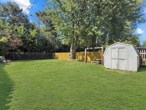 A backyard with a wooden shed, a picnic table, and a fenced area. - Cozy Vermilion Retreat Near Lake Erie - Sleeps 3 (Vermilion)