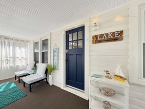 A room with a blue door, a white wall with a 'LAKE' sign, and a small shelf with decorative items. - Cozy Vermilion Retreat Near Lake Erie - Sleeps 3 (Vermilion)