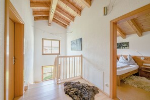 A room with a wooden ceiling, a bed with white bedding, a fur rug, and a painting on the wall. - Rauris House, Hohe Tauern National Park (Rauris)