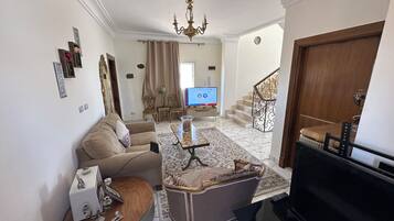 A living room with a sofa, a coffee table, a TV, and a staircase.