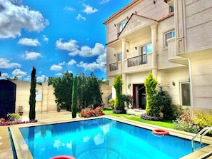 A swimming pool with a clear blue sky and a multi-story building with balconies.