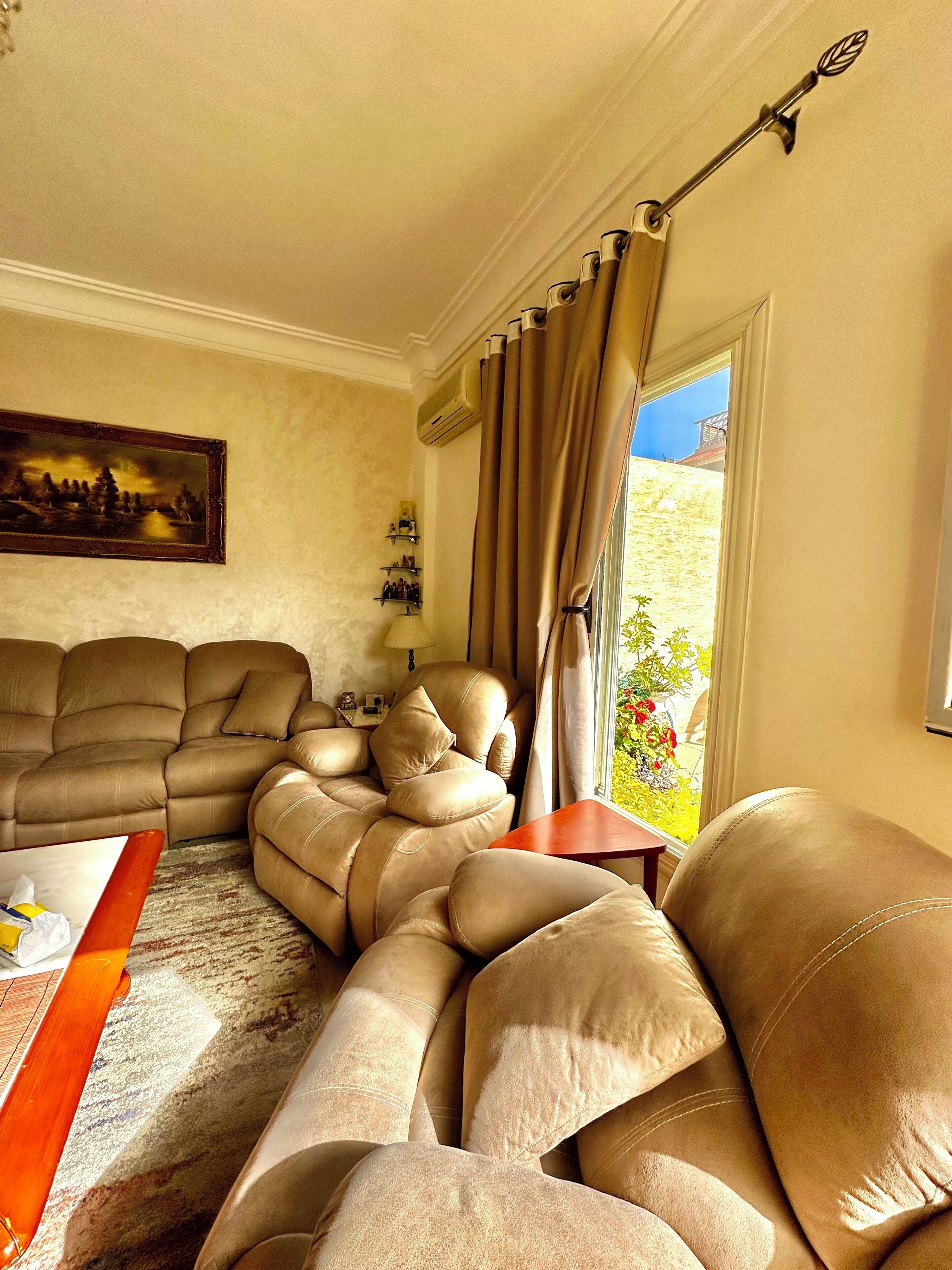 Una sala de estar con un sofá grande color beige, una mesa de centro de madera y un cuadro en la pared.