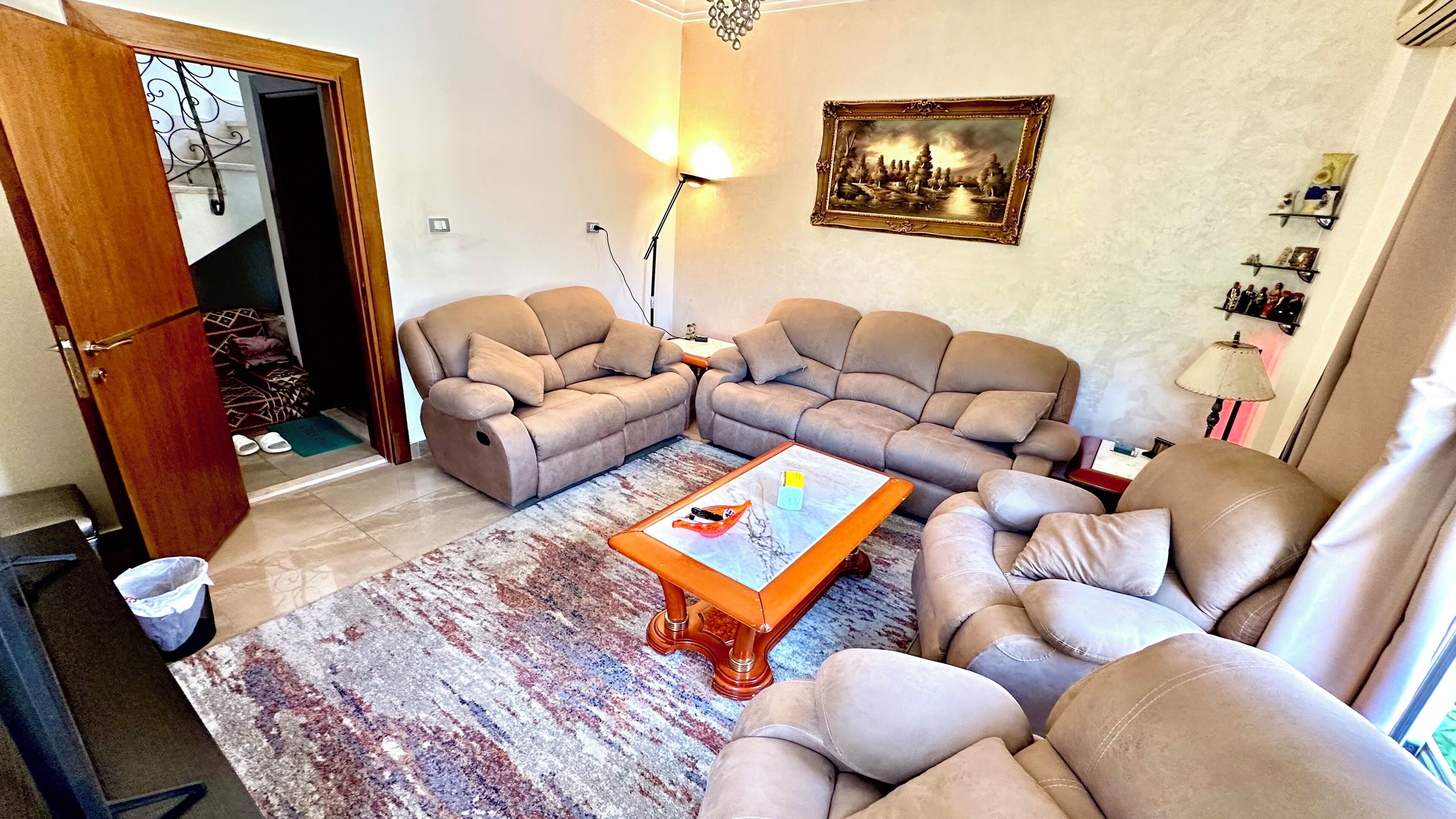 Ein Wohnzimmer mit einem Ecksofa, einem Couchtisch und einem gemusterten Teppich.