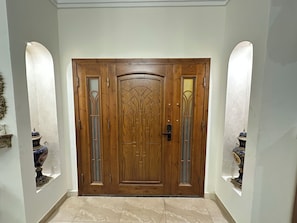 Una puerta doble de madera con paneles de vidrio y un picaporte de metal, flanqueada por dos luces empotradas.