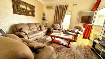 A living room with leather sofas, a coffee table, a painting, and a TV.