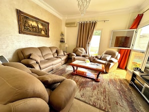 A living room with leather sofas, a coffee table, a painting, and a TV.