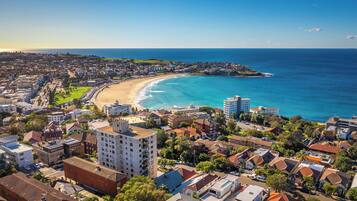 Un paysage urbain côtier avec une plage, des immeubles résidentiels et un ciel dégagé.