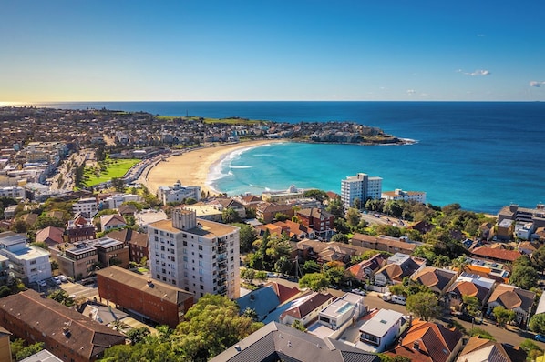 Un paysage urbain côtier avec une plage, des immeubles résidentiels et un ciel dégagé.