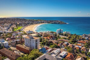 A coastal cityscape with a beach, residential buildings, and a clear sky. - Sydney Sun-soaked Sailing: A Luxurious Beach Experience (Sydney)