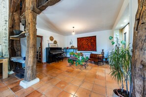 A spacious living area with a piano, a large abstract painting, and a variety of plants. - Holiday Home 'Domaine Liminalis' with Private Terrace, Garden and Wi-Fi (Saint-Martin-Petit)