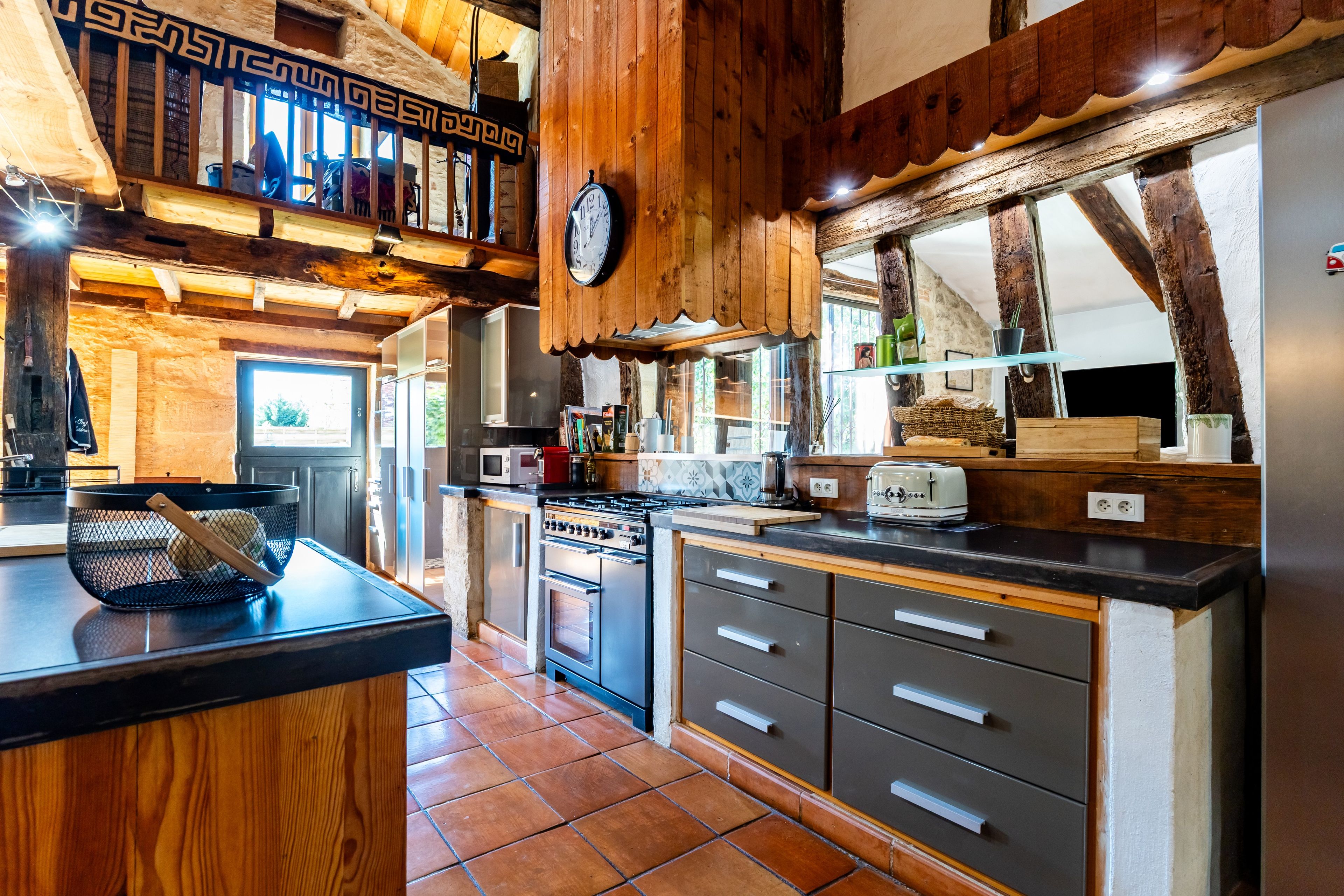 A kitchen with wooden beams, a stove, and a clock on the wall.