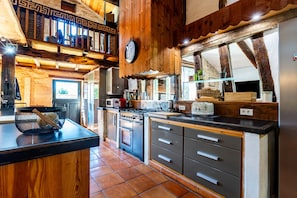A kitchen with wooden beams, a stove, and a clock on the wall. - Holiday Home 'Domaine Liminalis' with Private Terrace, Garden and Wi-Fi (Saint-Martin-Petit)