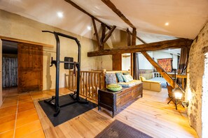 A room with a wooden ceiling, a bed with patterned bedding, a workout station, and a rustic wooden bench. - Holiday Home 'Domaine Liminalis' with Private Terrace, Garden and Wi-Fi (Saint-Martin-Petit)