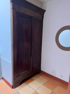 Habitació cantonera amb un armari de fusta fosca, un sòl de rajola i una decoració circular a la paret.