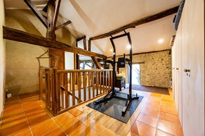 A room with a wooden staircase, a black exercise machine, and a stone wall. - Holiday Home 'Domaine Liminalis' with Private Terrace, Garden and Wi-Fi (Saint-Martin-Petit)