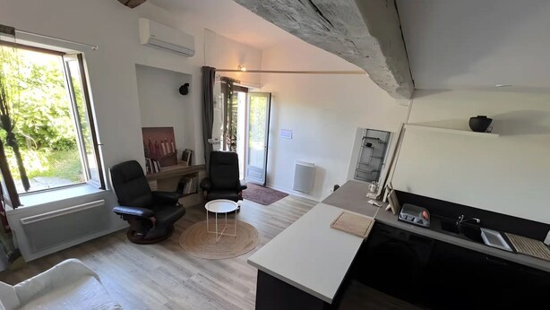 A modern living room with a large window, a fireplace, and a kitchen area with a dining table. - “Liminalis” Apartment with Private Terrace, Garden, and Wi-Fi (Saint-Martin-Petit)