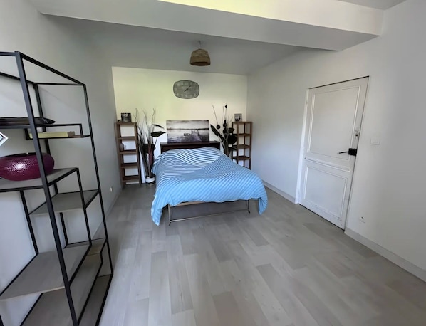 A bedroom with a bed, a wardrobe, a shelf unit, and a clock on the wall.