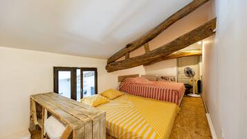 A bedroom with a wooden bed frame, a small wooden table, and a fan.