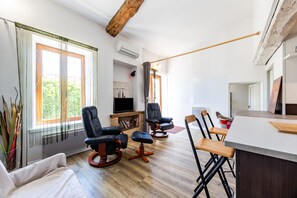 A modern living room with a fireplace, a flat-screen TV, and a dining area with bar stools.