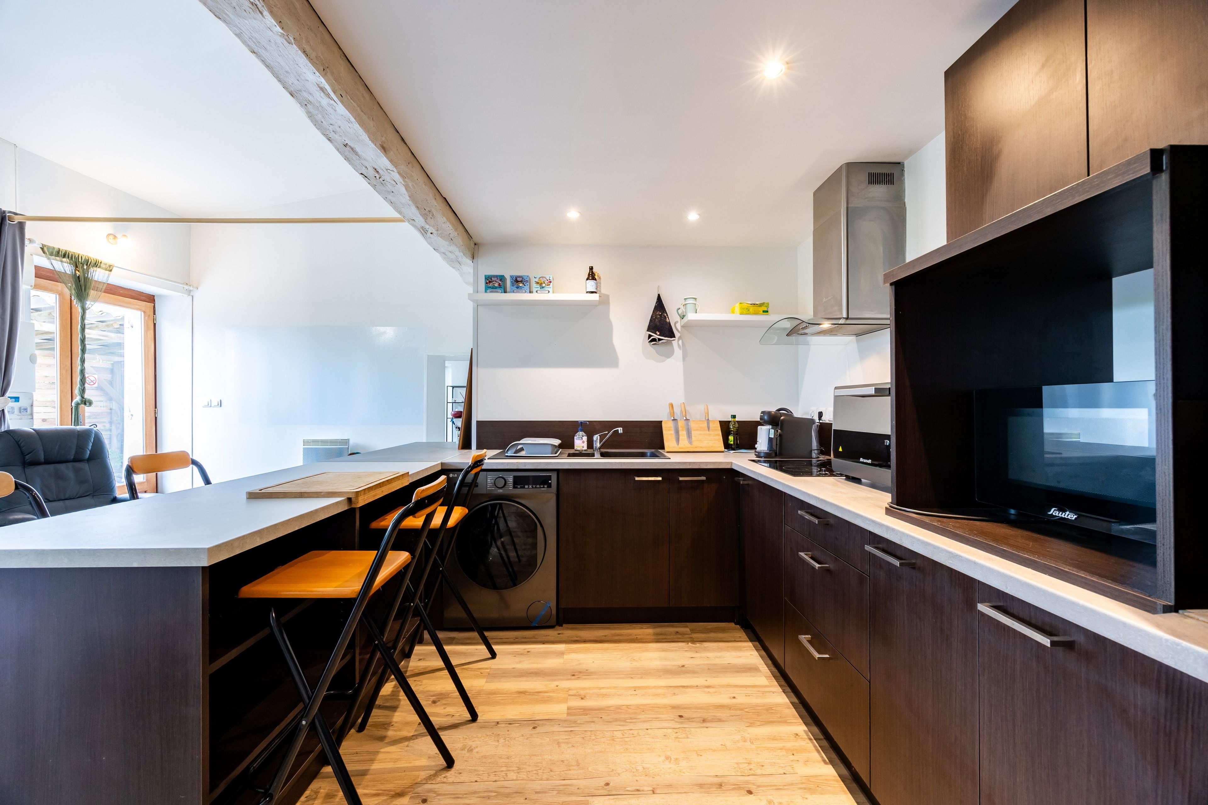 Une cuisine moderne équipée d’un lave-vaisselle intégré, d’un grand téléviseur à écran plat et d’un plancher en bois.