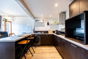 A modern kitchen with a built-in dishwasher, a large flat-screen TV, and wooden flooring.