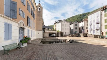 Ein Innenhof mit einem Brunnen, einer Bank und Gebäuden im traditionellen Baustil.