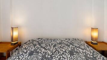 Ein Bett mit einem gemusterten Überwurf, zwei Nachttischlampen und einem Holznachttisch.