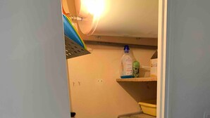 Un cuarto de lavandería con lavadora, un tendedero y estantes con productos de limpieza.
