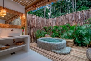 A bathroom with a white sink, shelves, and a stone hot tub.