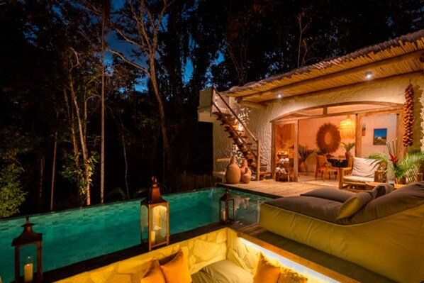 A poolside area with a sofa, a staircase leading to an upper level, and a dining area with a table and chairs.