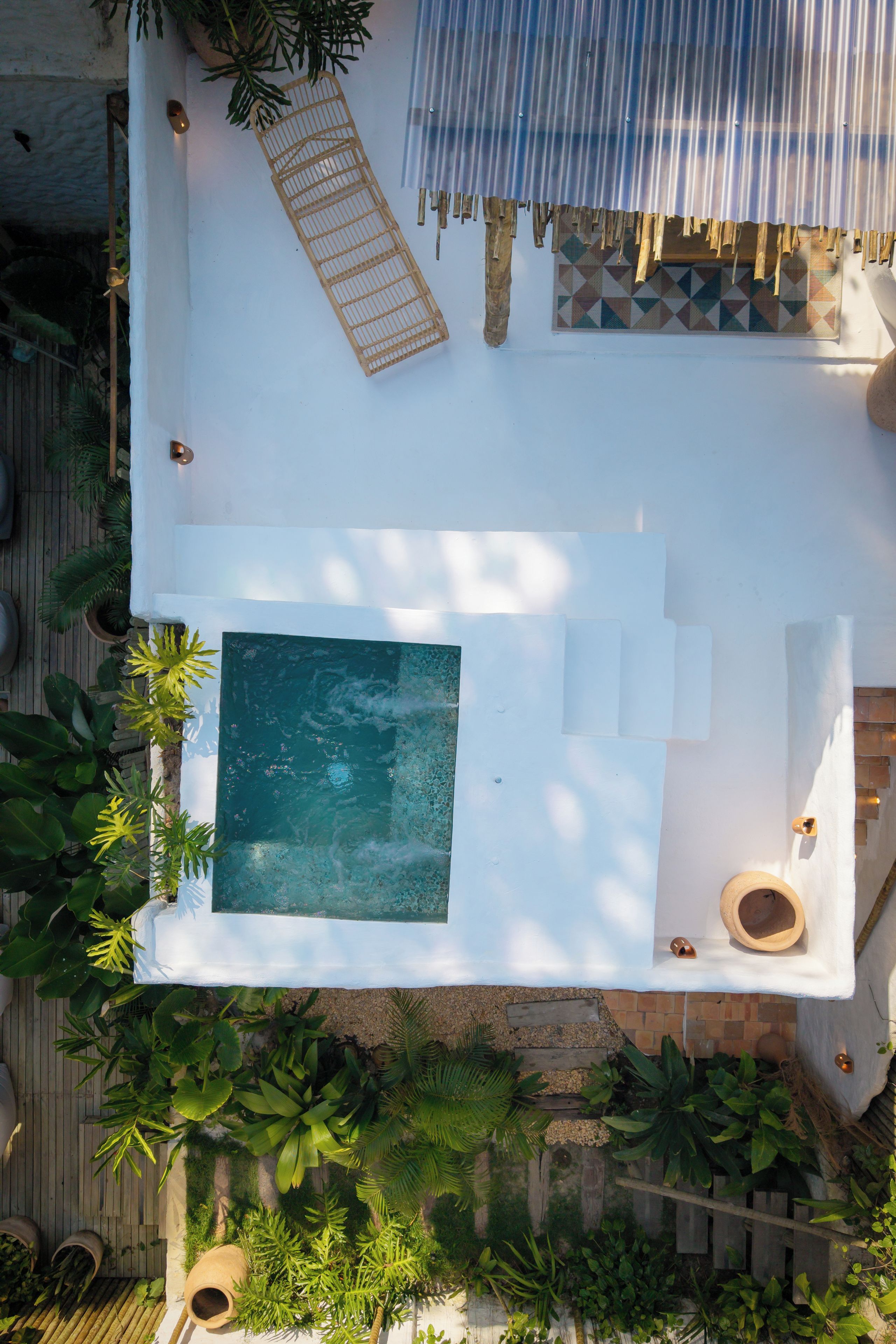 Vista aérea de uma área de piscina no terraço, com piscina retangular, espaço para sentar e vegetação ao redor.