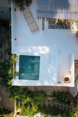 An aerial view of a rooftop pool area with a rectangular pool, seating, and surrounding vegetation. - Vila Bem Te Vi (Porto Seguro)