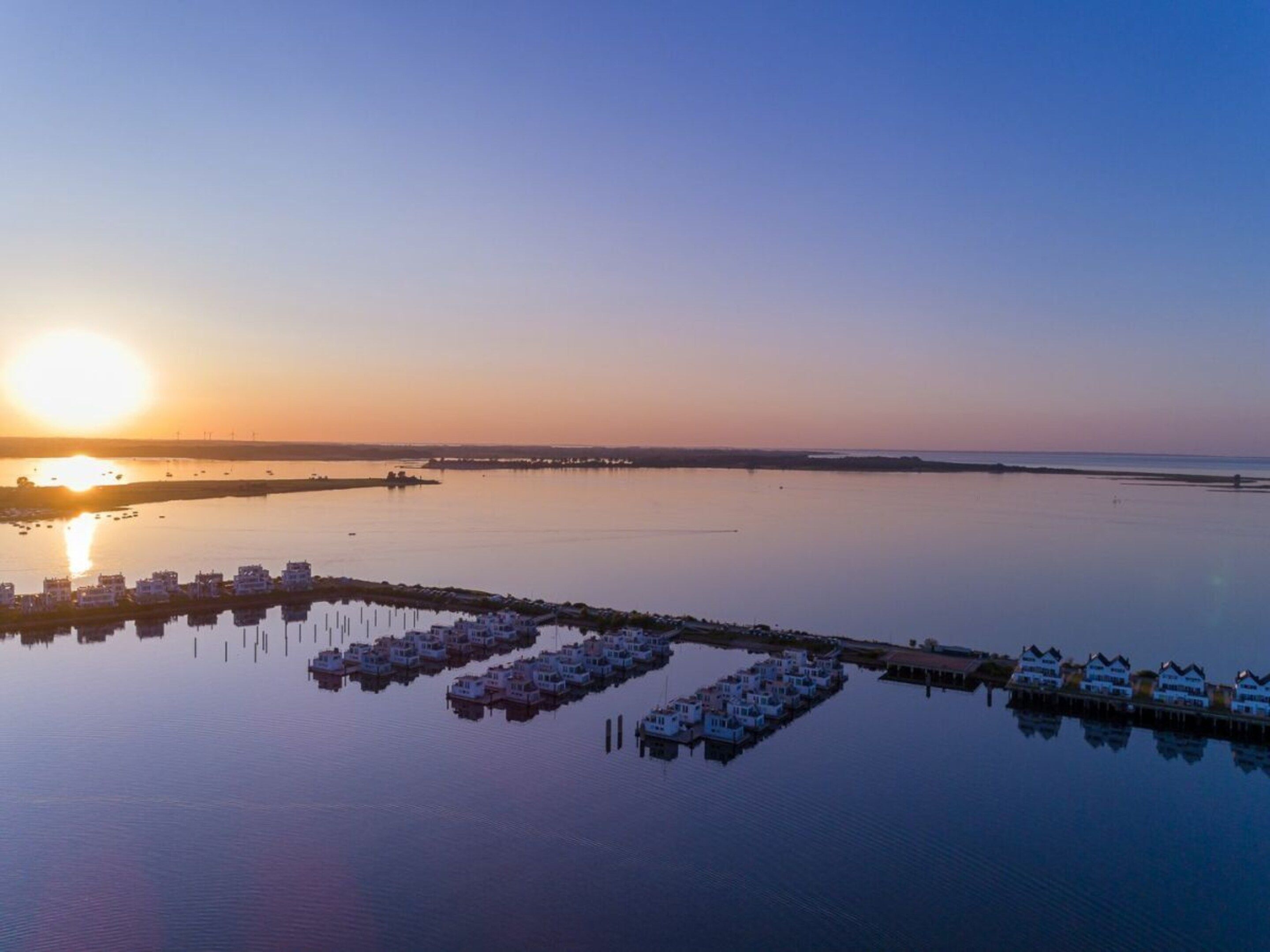 A marina with docked boats and a row of houses.