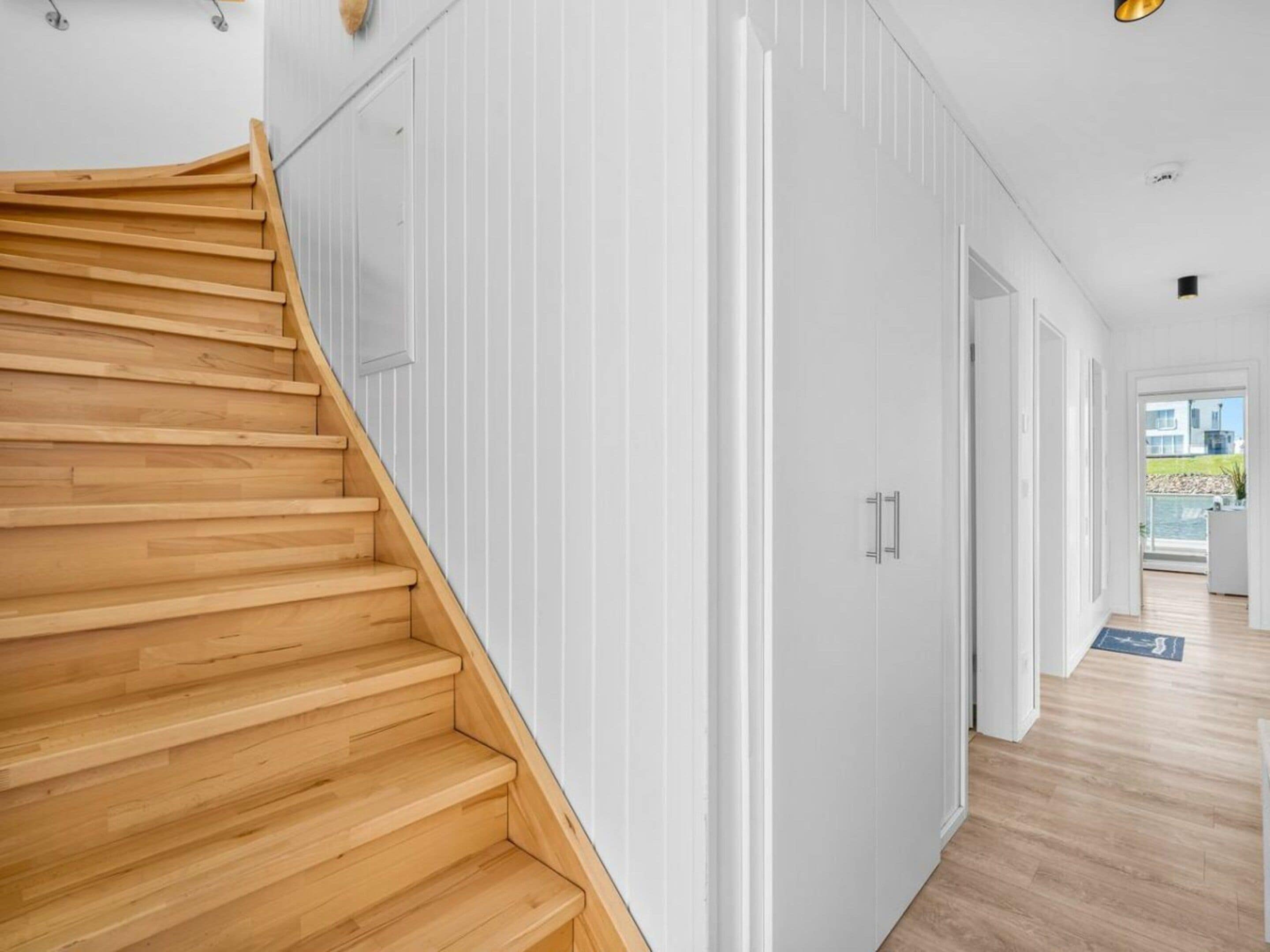 A modern interior with a wooden staircase leading to a room with white walls and a door.