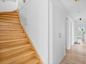A modern interior with a wooden staircase leading to a room with white walls and a door. - Holiday Home in Olpenitz With Swimming Pool (Kappeln)