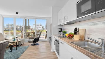 A modern kitchen with a Bosch microwave, a sink, and a countertop with a fruit bowl and knives.