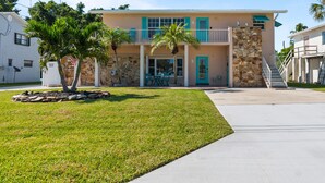 A two-story house with a stone facade, a front porch, and a well-maintained lawn. - Intercoastal Cove Retreat - Upstairs Island Escape with Water Views (Fort Pierce)