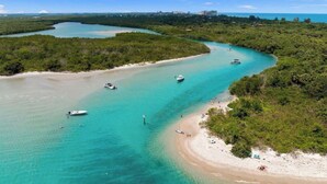 A coastal landscape with clear turquoise waters, boats, and a sandy beach. - Intercoastal Cove Retreat - Upstairs Island Escape with Water Views (Fort Pierce)