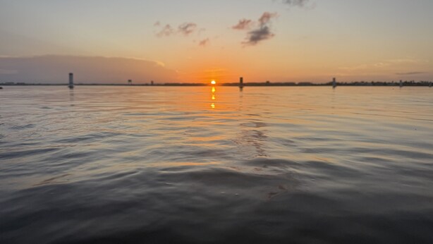 A sunset over a calm body of water with a distant shoreline. - Intercoastal Cove Retreat - Upstairs Island Escape with Water Views (Fort Pierce)