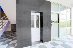 A modern interior with a checkered floor, a staircase, and a door with a glass panel.