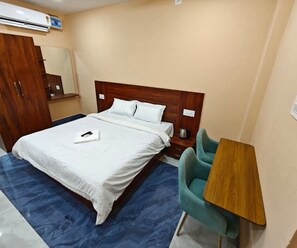 Een hotelkamer met een bed, een bureau, een stoel, een kledingkast en een airconditioning.