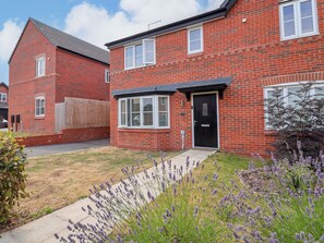 A red brick house with a black front door, white windows, and a number '12' sign. - Corbetts Close (Crewe)