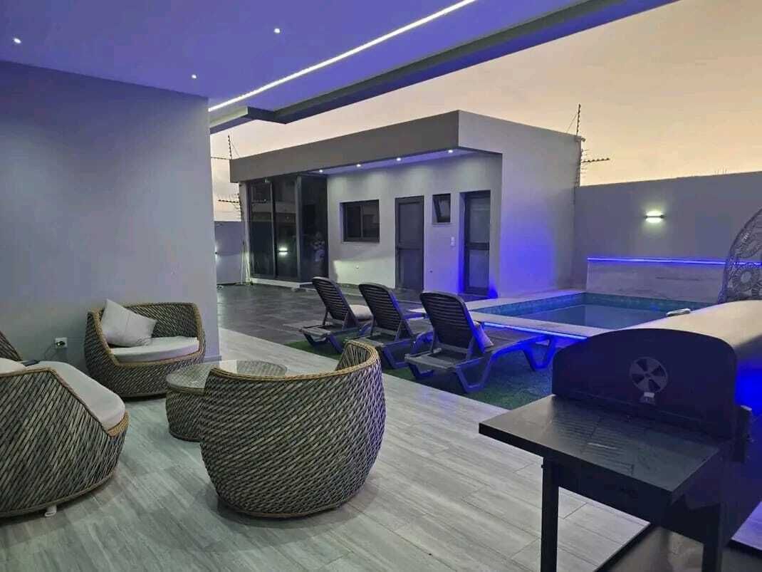 Espaço moderno de piscina interna com espreguiçadeiras e churrasqueira.