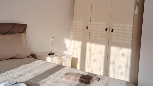 Et soveværelse med seng, garderobe og et natbord.