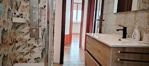 A bathroom with a shower, a sink, and a mirror. - Vrbo Property (Moneglia)